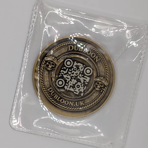 A Dubloon sealed in a clear plastic sleeve, mark side up